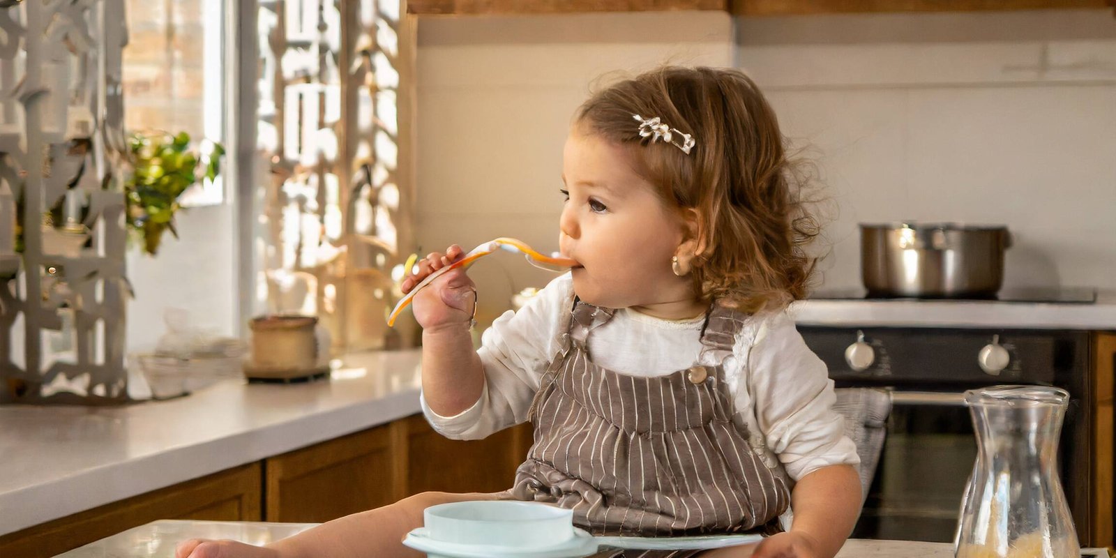 Firefly bebe qui mange dans une belle et grande cuisine beige et marron avec des accessoires en plas uai